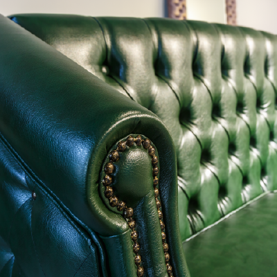 sofá de pien en color verde donde se observan los detalles de las tachuelas.