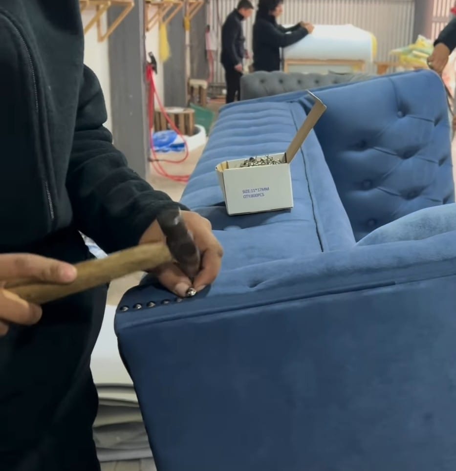 Compañero trabajando en el tapizado de un sofá azul en el Taller Tapiceria Centro